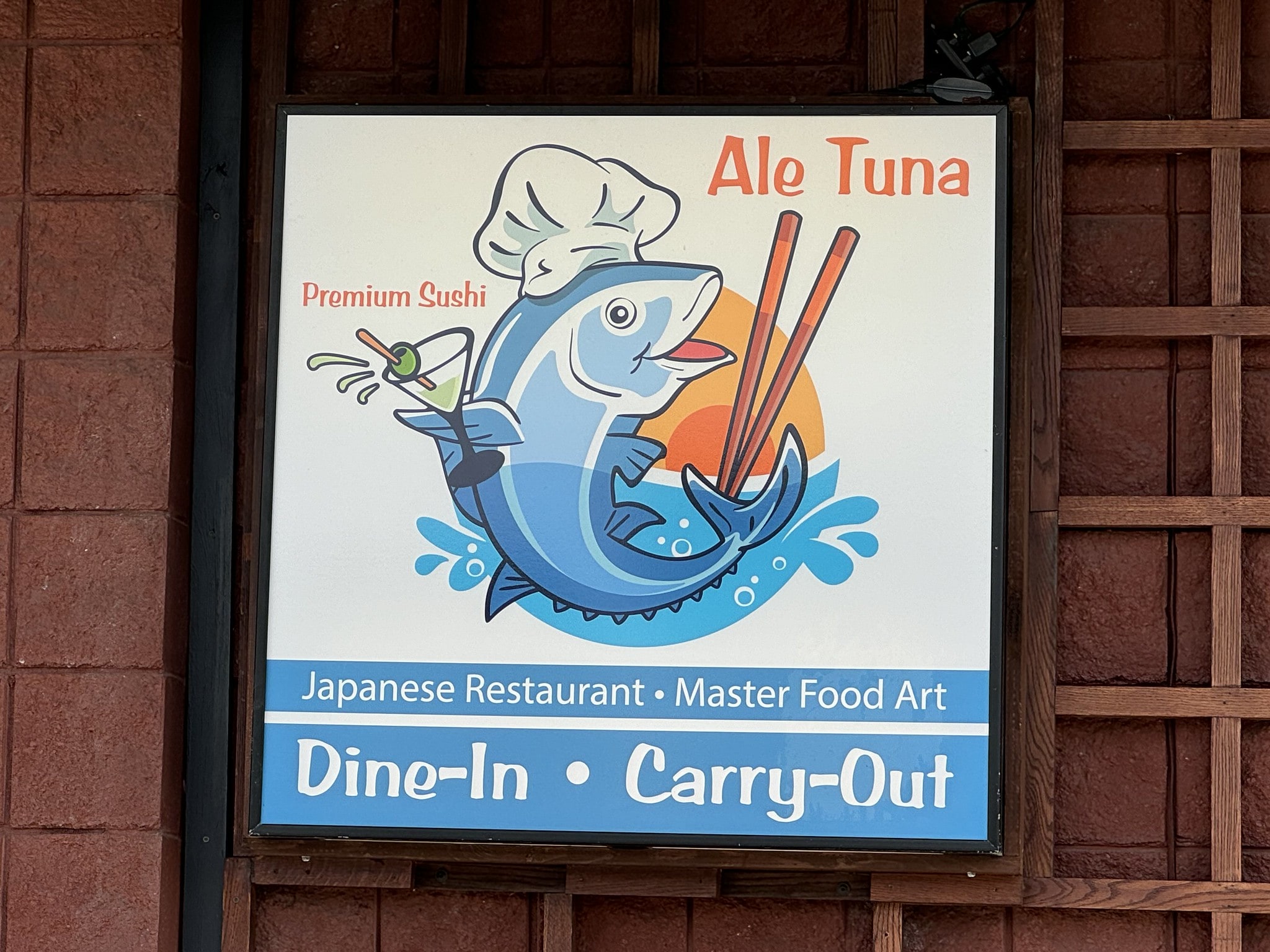 Sign for "Ale Tuna," a Japanese restaurant. The sign features a cartoon tuna chef holding sushi and chopsticks. It advertises dine-in and carry-out options with the tagline "Master Food Art.