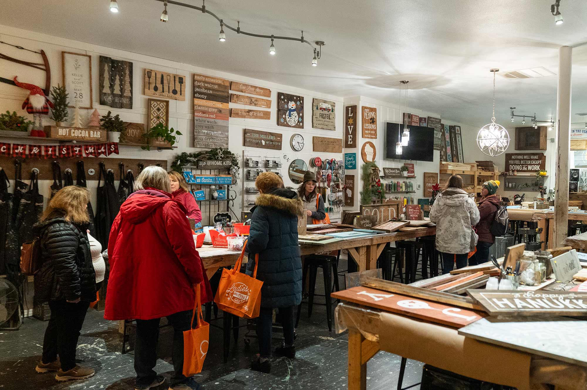 A group of people in a store filled with various wall decorations and crafts. Some individuals are talking while others are browsing around the displayed items.