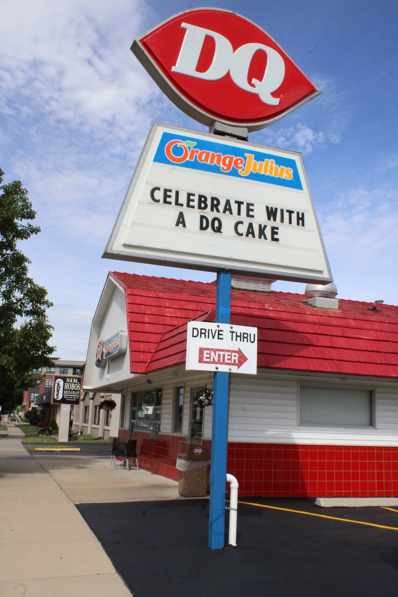 Image of a Dairy Queen restaurant with a red roof. The sign reads, "Orange Julius. Celebrate with a DQ Cake." A drive-thru sign below directs vehicles to enter.