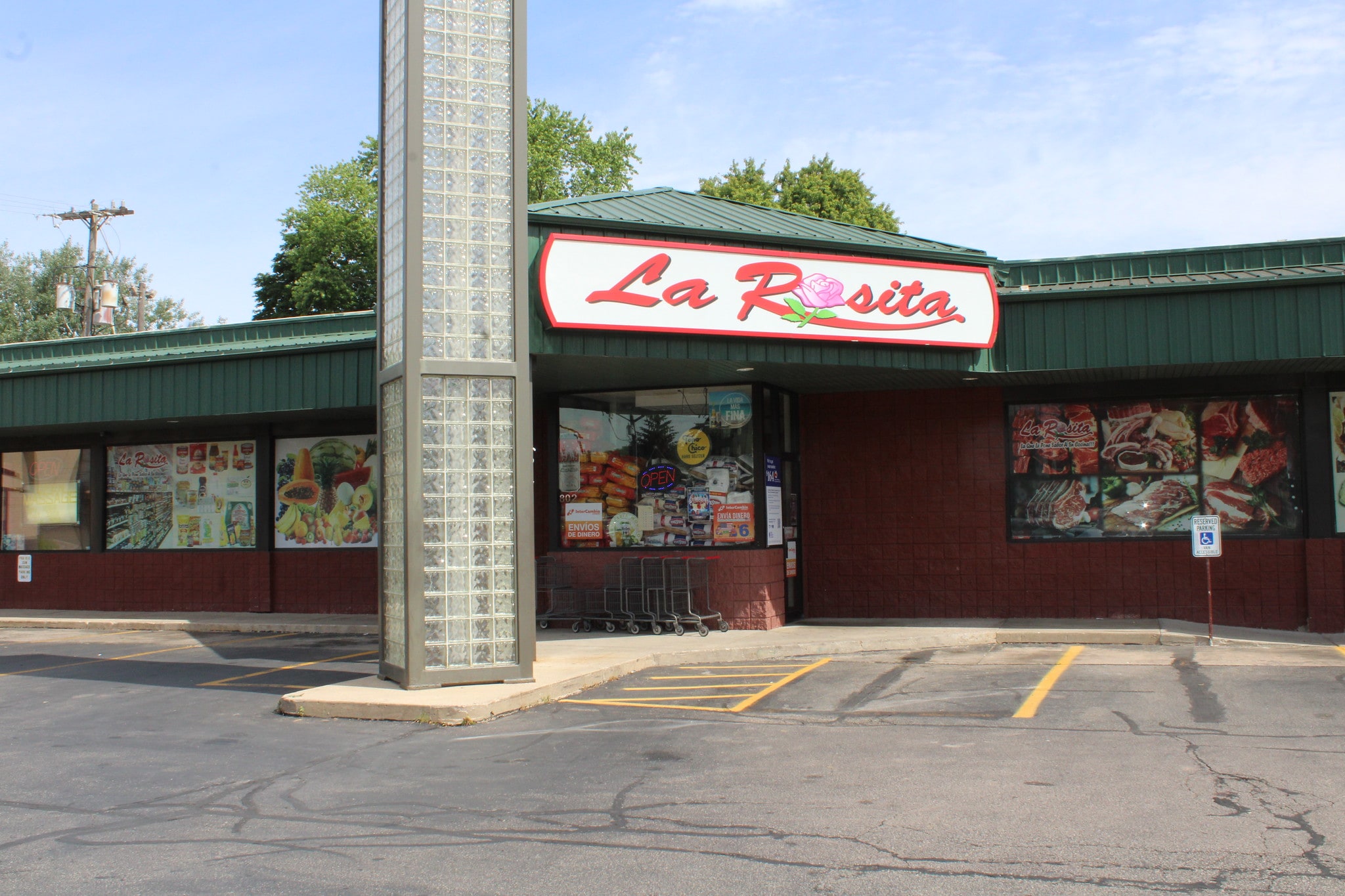 Exterior of La Rosita store with large sign, green awning, and glass block column. There are shopping carts outside and a handicapped parking space in front.