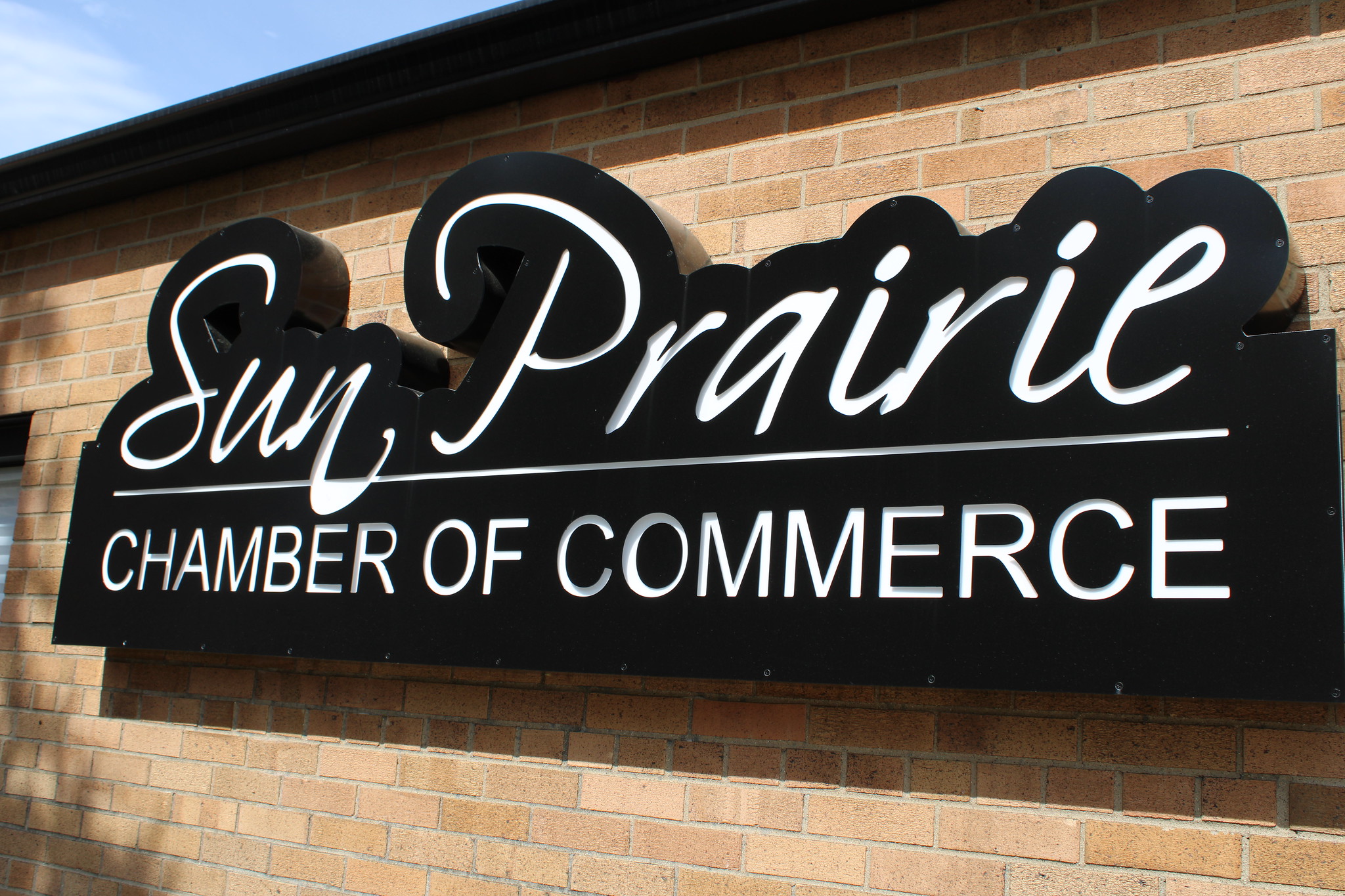 Sign for the Sun Prairie Chamber of Commerce mounted on a brick wall.