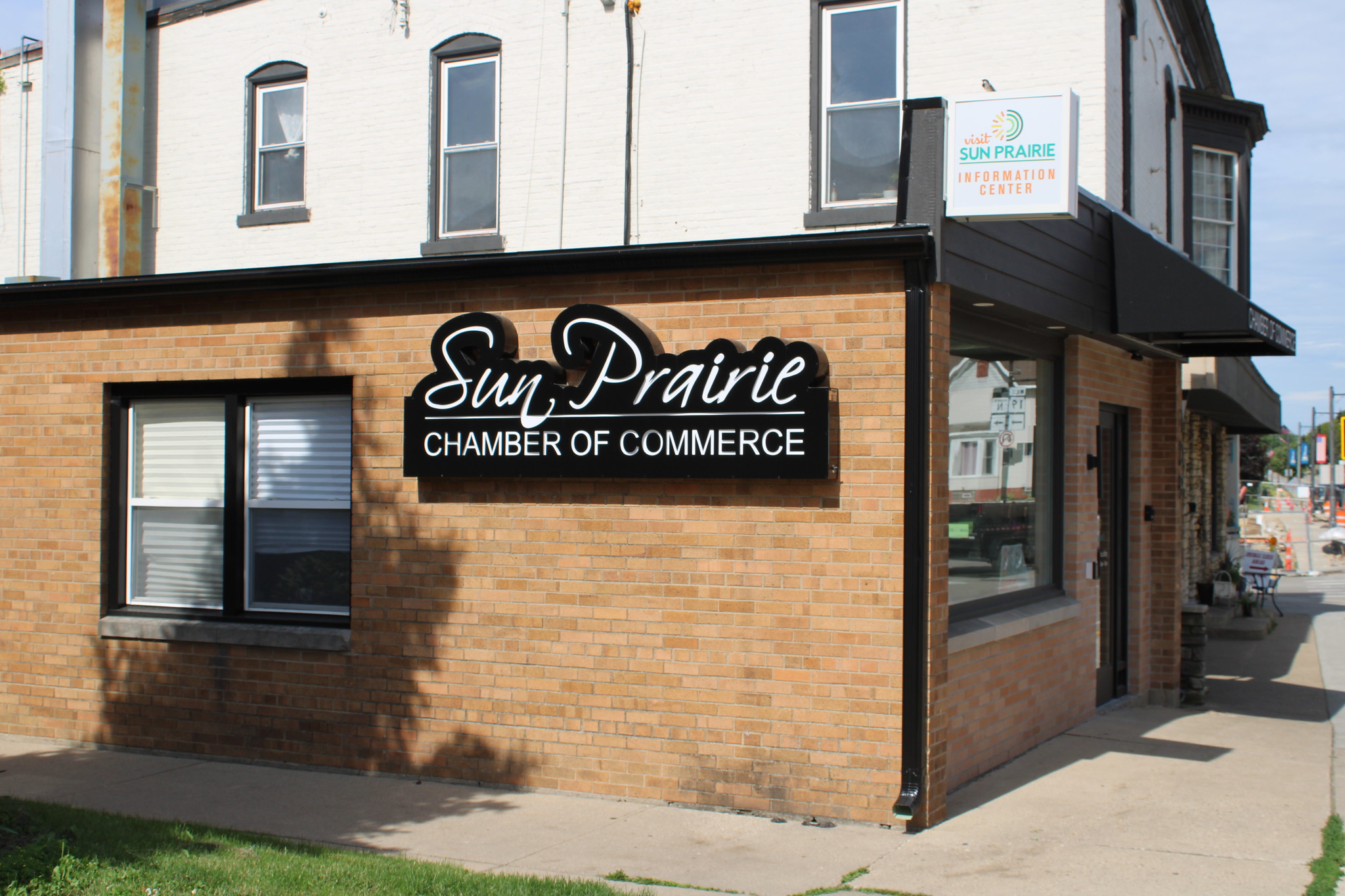 Image of the Sun Prairie Chamber of Commerce building with a sign on the wall reading "Sun Prairie Chamber of Commerce" and another sign above the entrance for the Sun Prairie Information Center.