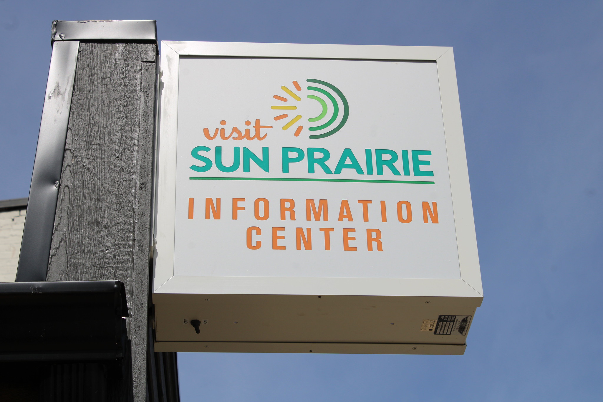 A sign for the Sun Prairie Information Center with the text "Visit Sun Prairie Information Center" against a clear blue sky.