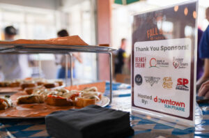 A table with a tray of appetizers and a sign listing sponsors for the Fall Beer Taste event, hosted by Downtown Sun Prairie.