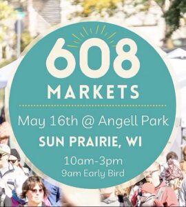 Circular sign for "608 Markets" event at Angell Park in Sun Prairie, WI, on May 16th, 10am-3pm with 9am early bird. Blurred crowd and tents in the background.