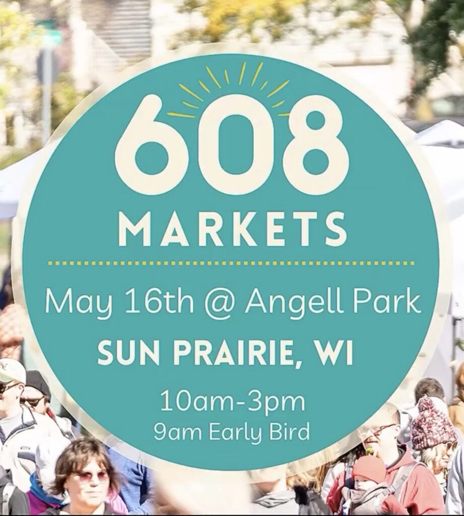 Circular sign for "608 Markets" event at Angell Park in Sun Prairie, WI, on May 16th, 10am-3pm with 9am early bird. Blurred crowd and tents in the background.