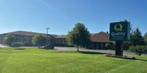Quality Inn & Suites hotel with a large green lawn and a clear blue sky in the background.